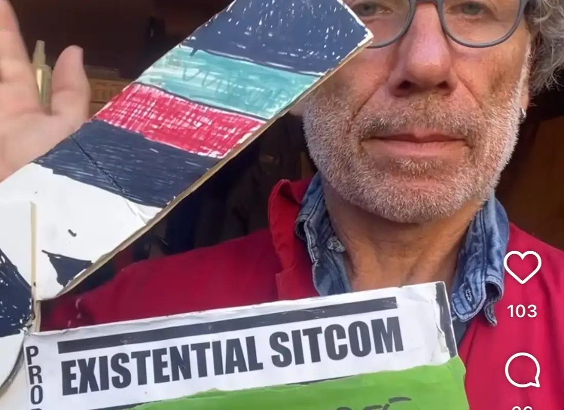 A man with a clapper board saying existential sitcom